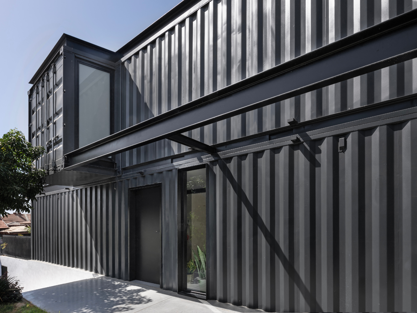 כניסה לחדר מרחף מעל חזית צדדית של בית בנוי ממכולות יד שנייה