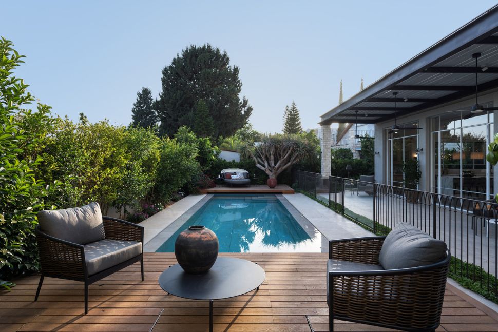 החצר האחורית בה פרגולה מברזל נתמכת בעמודים ובריכת שחיה חצר אחורית עם בריכת שחיה