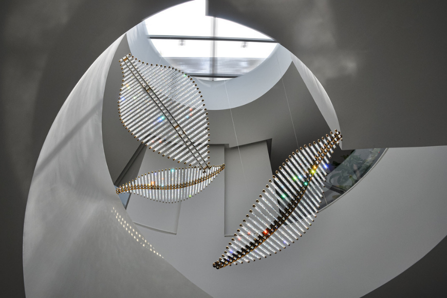 גרם מדרגות ספירלי מודרני עם סקיילייט עגול ותאורת קריסטל תלויה בעיצוב אמנותי יוקרתי.