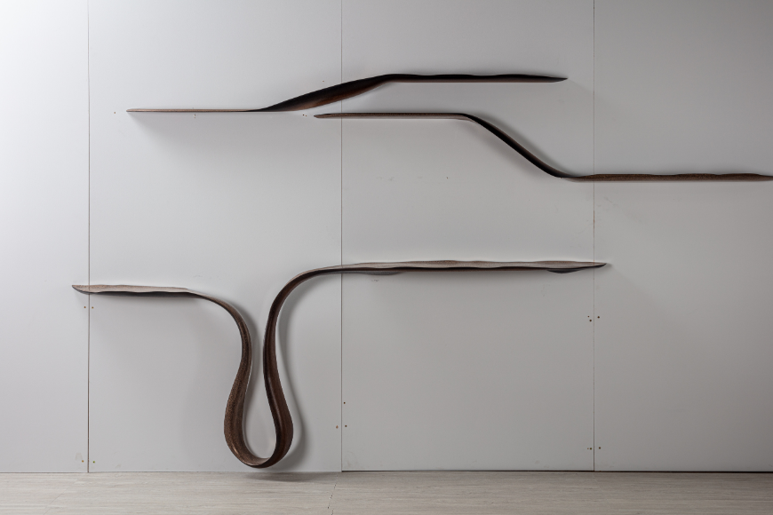 מדפי עץ מעוצבים בצורת גל על קיר לבן מינימליסטי